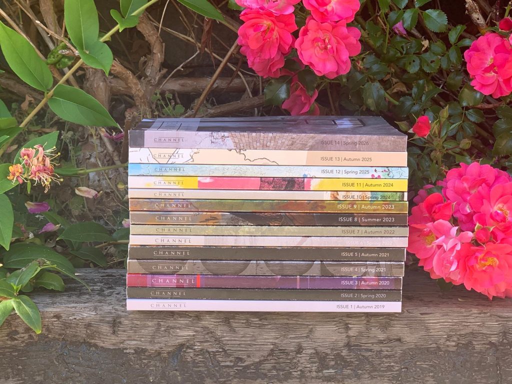 Photo of a pile of books sitting outdoors, surrounded by pink flowers