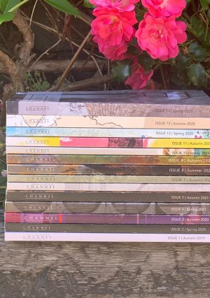 Photo of a pile of books sitting outdoors, surrounded by pink flowers
